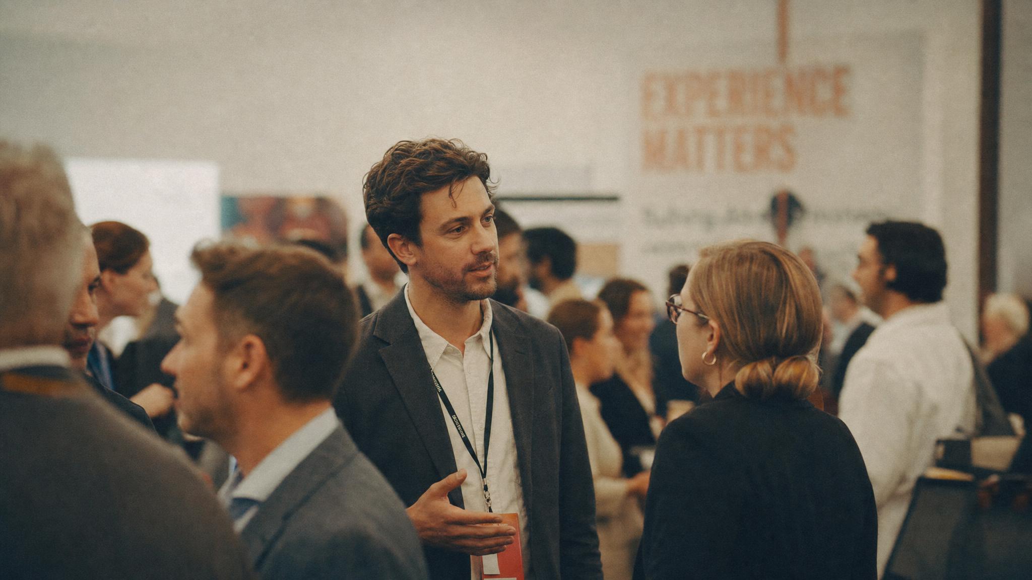 Two people in animated conversation on a crowded conference floor.